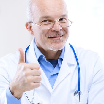 Friendly smiling doctor with thumbs up at the hospital.