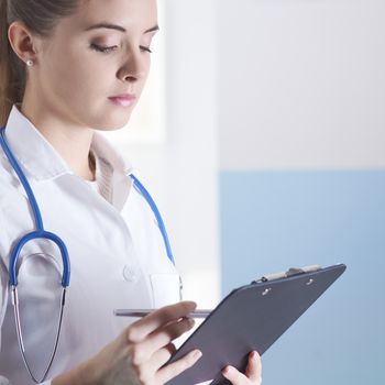 Young woman doctor or pharmacist in office with clipboard