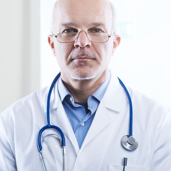 Confident doctor looking at camera with hospital in the background.