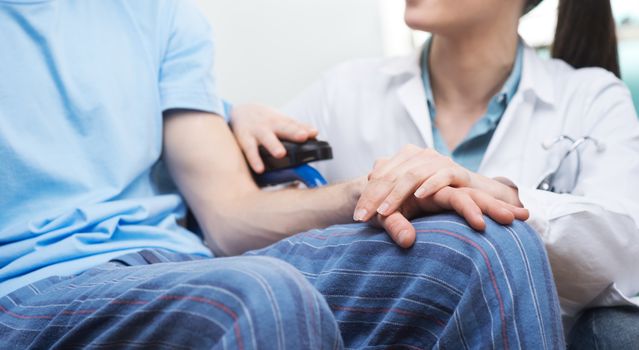 Young female doctor comforting a young patient on wheelchair.