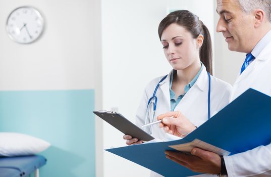 Young assistant and doctor checking medical records and documents.