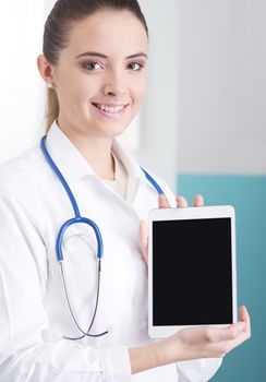 Portrait of a beautiful young female doctor in scrubs with stethoscope around neck holding digital tablet.