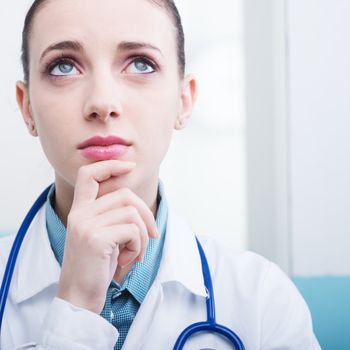 Portrait of a young female doctor thinking and looking up