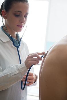 Female doctor listening man's back through stethoscope 