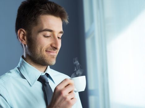 Businessman having a coffee break and relaxing at window.