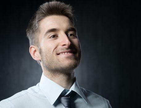 Smiling elegant man looking away on dark gray background.