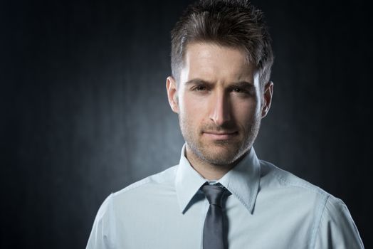 Young businessman looking at camera with doubtful expression.