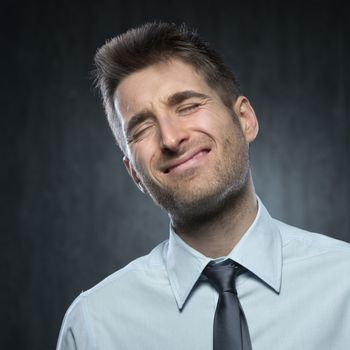 Young man with painful expression on dark background.