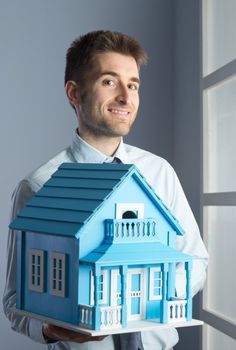 Friendly real estate agent with light blue model house.