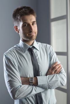 Confident businessman with arms crossed smiling at camera.