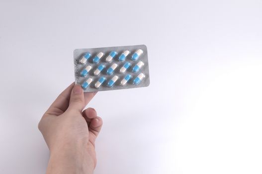 Caucasian Woman Holding a Blister Pack of Pills on White Background / Capsules and Pills / Medicine