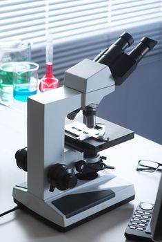 Microscope close-up and laboratory equipment on a desk.