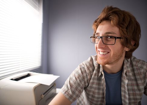 Funny nerd guy with glasses smiling, office on background.