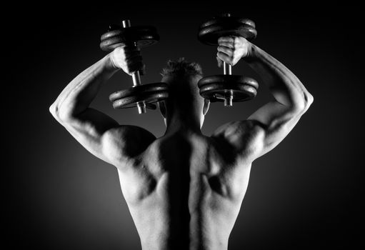 Muscular attractive man weightlifting on dark background.