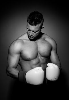 Boxer posing on dark background with fists raised.