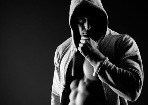 Confident body builder in hooded shirt with bare chest.
