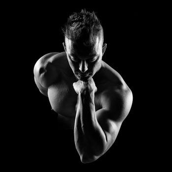 Body builder posing and showing bicep muscle on dark background.