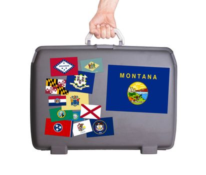 Used plastic suitcase with stains and scratches, stickers of US States, Montana