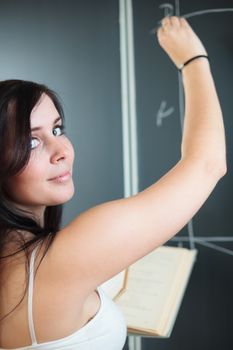 Pretty, young college student drawing on the chalkboard/blackboard during a math class (shallow DOF; color toned image)