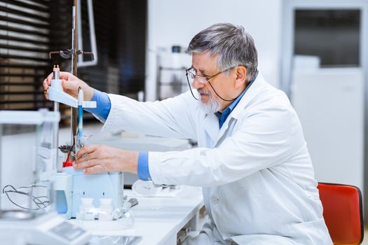 Senior male researcher carrying out scientific research in a lab (shallow DOF; color toned image)