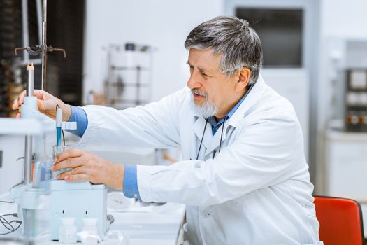 Senior male researcher carrying out scientific research in a lab (shallow DOF; color toned image)