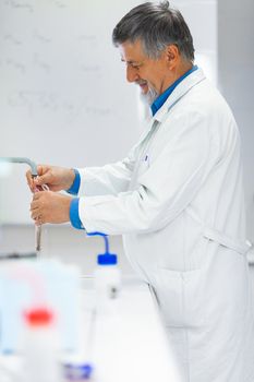 Senior male researcher carrying out scientific research in a lab (shallow DOF; color toned image)