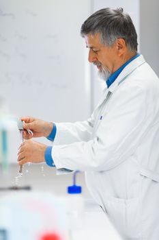 Senior male researcher carrying out scientific research in a lab (shallow DOF; color toned image)