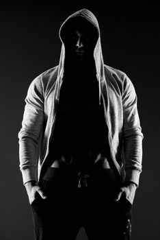 Confident body builder in hooded shirt with bare chest.