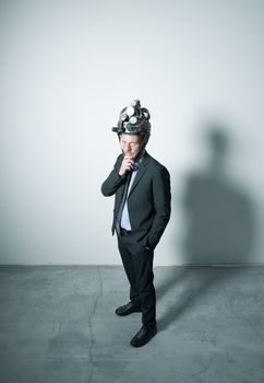 Confident businessman thinking with hand on chin wearing steampunk helmet