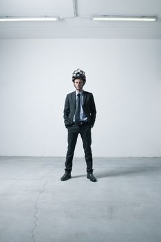Confident businessman standing in an empty room with futuristic helmet.