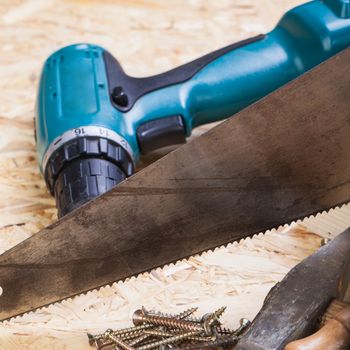 Battery-operated portable hand drill with timber, screwdrivers and screws surrounded by fresh wood shavings in a carpentry, joinery, DIY or construction concept