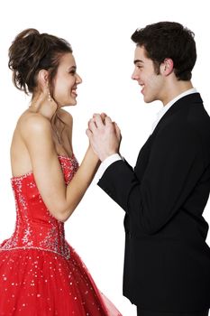 First love.  Boy & girl, in formal attire, holding hands & smiling at each other.