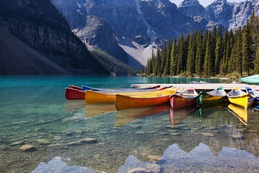 Morning light on colorful canoes along the shore of Moraine Lake, Banff National Park, Alberta, Canada.