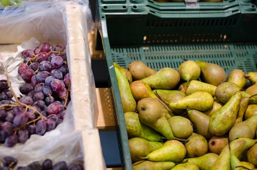 green fresh pear and grapes bunch in plastic box in store