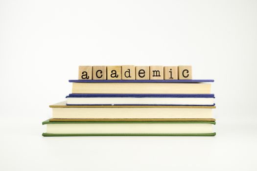 academic word on wood stamps stack on books, business and education concept