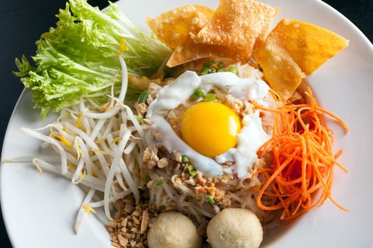 Gai pad bai gaprow style Thai dish with fried egg and rice noodles.