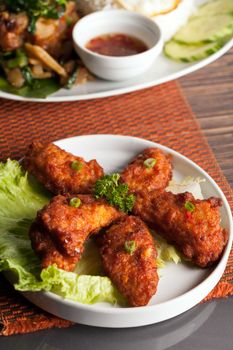 Thai style spicy chicken wings on a round white plate.