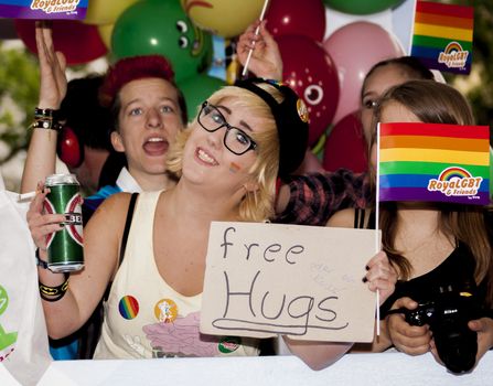 BERLIN, GERMANY - JUNE 21, 2014: Christopher Street Day.Happiness young woman offer free hugs  Crowd of people Participate in the parade celebrates gays, lesbians, bisexuals and transgenders.