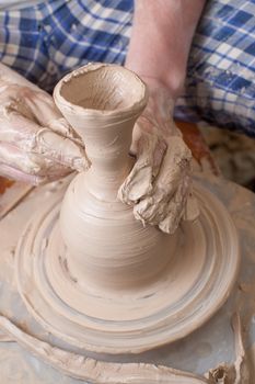 Hands of a potter, creating an earthen jar on the circle