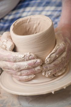 Hands of a potter, creating an earthen jar on the circle