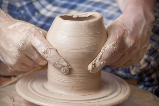 Hands of a potter, creating an earthen jar on the circle