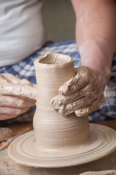 Hands of a potter, creating an earthen jar on the circle