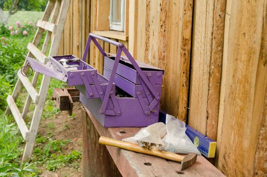 purple toolbox and hammer nail on wooden table outdoor