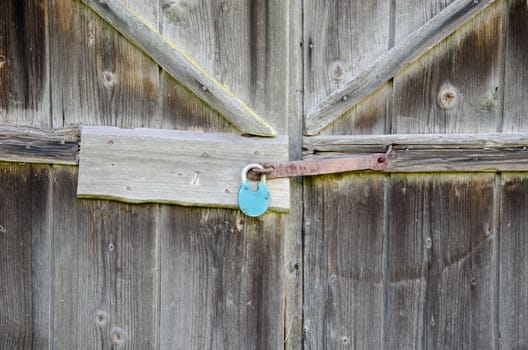 rural wooden barn door with iron blue lock hanging