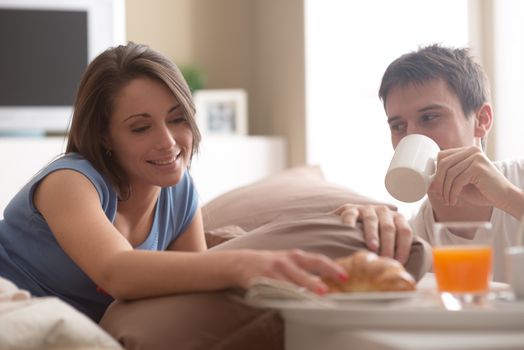 Beautiful smiling young couple having breakfast in bed