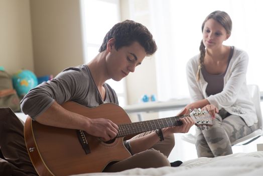 Young handsome man playing guitar for his girlfriend