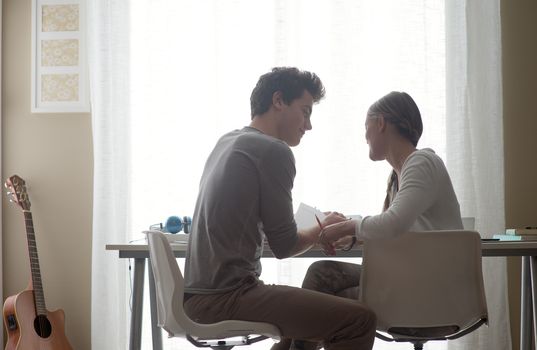 Teen boy and girl sitting together and studying at home