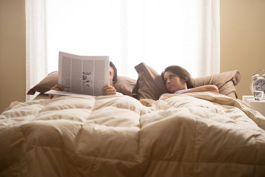 Man reading a newspaper while her wife waiting...