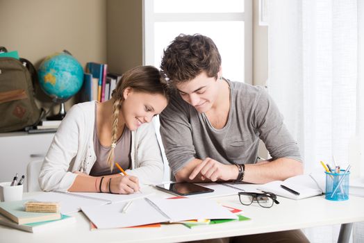 Teen boy and girl sitting together and studying 