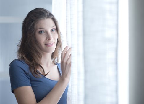 Smiling woman standing near window early in the morning 
